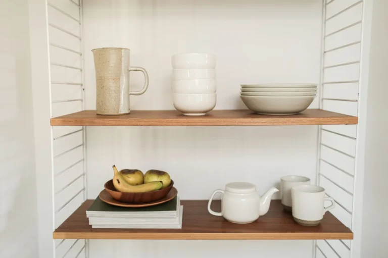 Tidy kitchen shelf beside a drawer where lids stand on edge in one rank